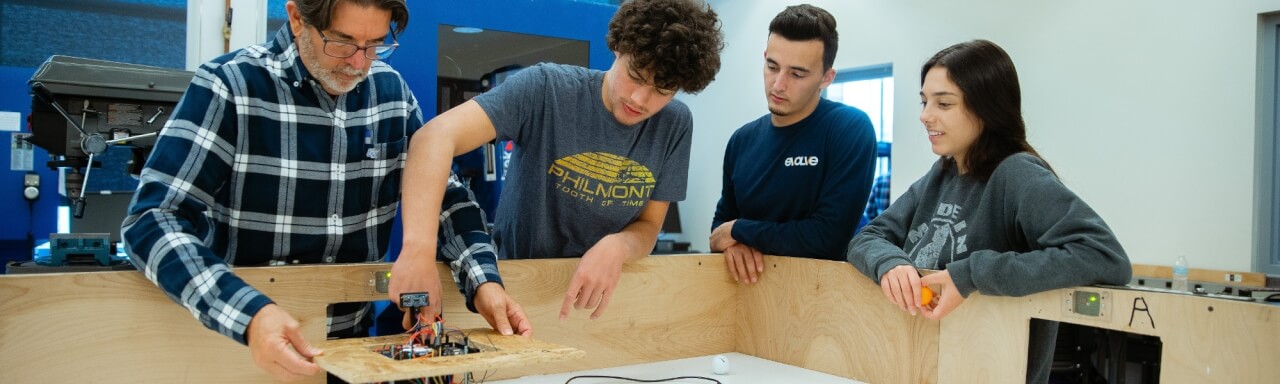 Students working on a robot with faculty